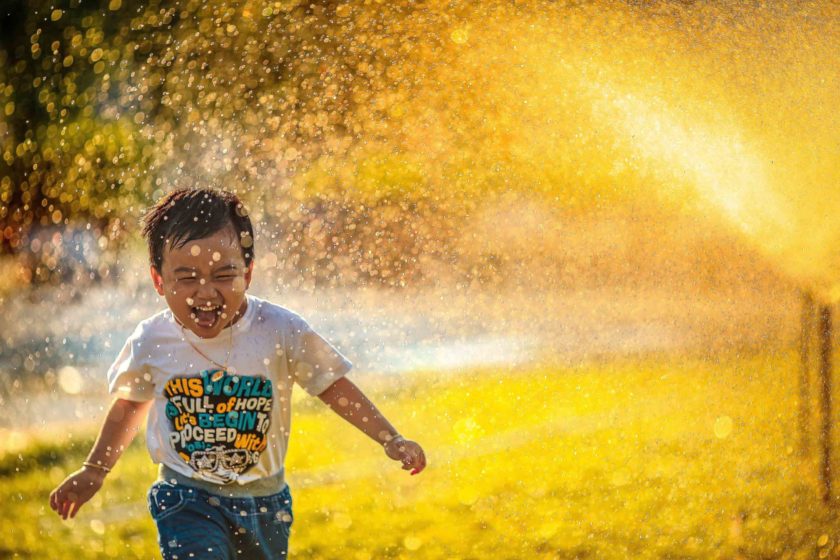 A child running through a sprinkler.