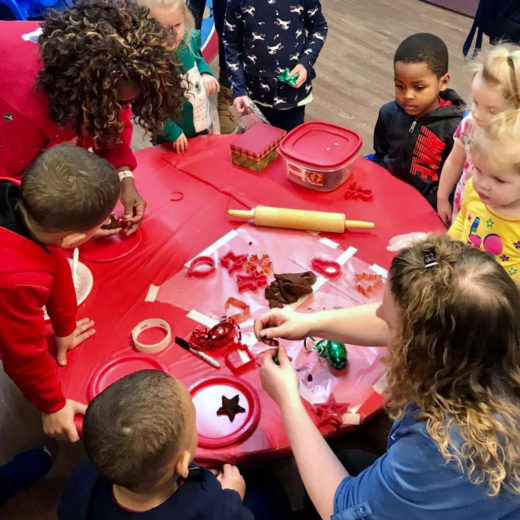 Children doing crafts at a red table.