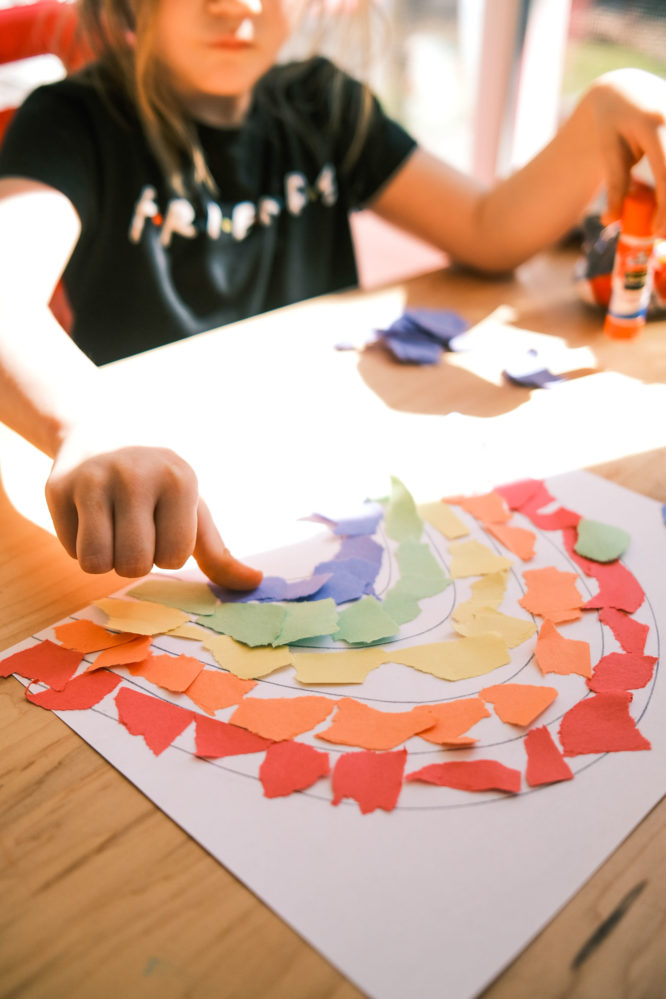 A young girl crafting a rainbow with construction paper.