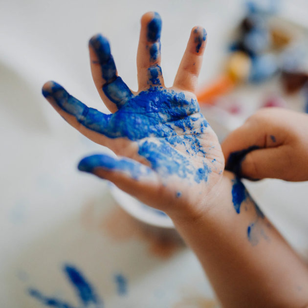 A toddlers hand with paint on it.