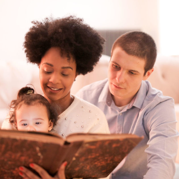 A couple reading with their baby.