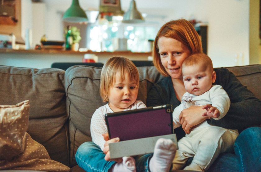 Two children sitting on a couch with their mother.