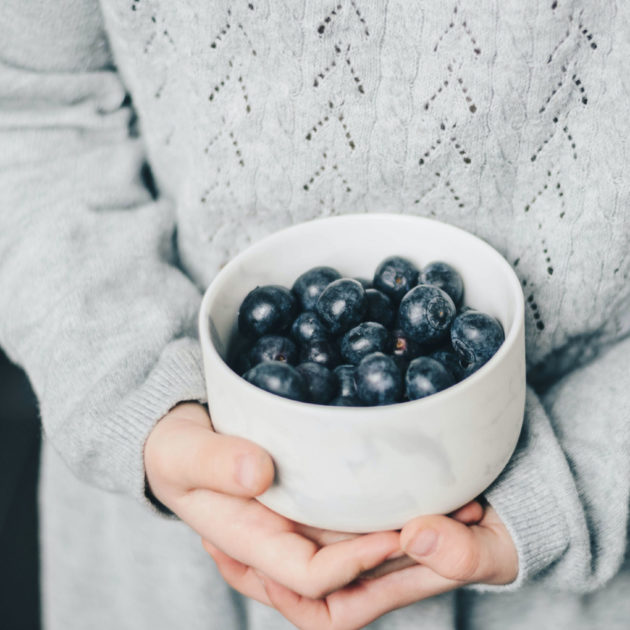 Child holding a cup of blueberries.