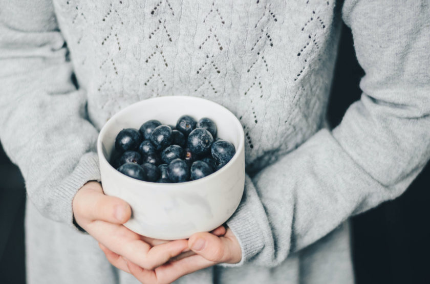 Child holding a cup of blueberries.