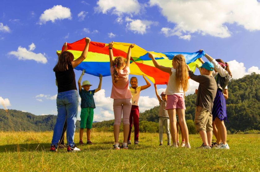 A group of children playing with a parachute.