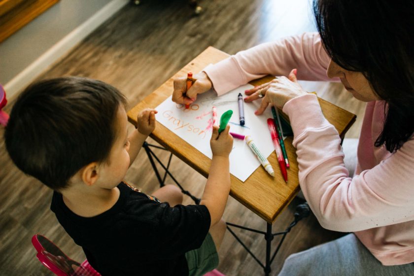 A teacher helping a little boy.