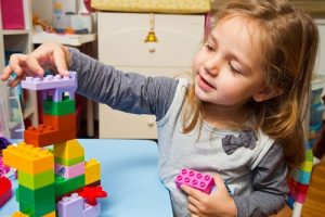 A young girl playing with legos in a room.