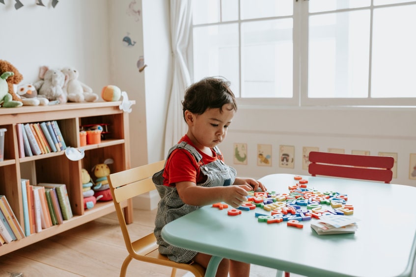 A young child playing with colorful alphabet blocks.