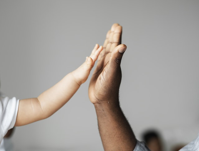 A child holding her hand up to an adult.