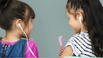 Two young girls sharing earbuds.