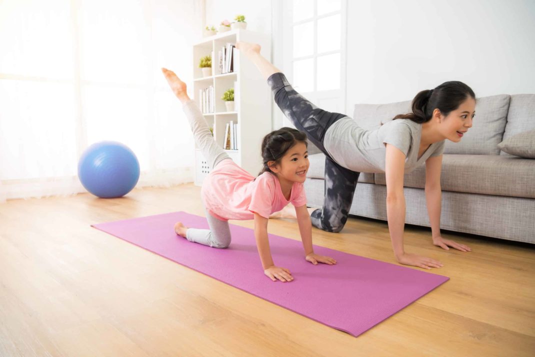 A woman and a child doing yoga in the living room.