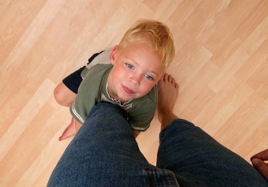 A young boy is standing on a wooden floor.