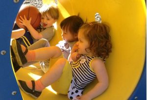 A group of children are playing on a slide at a playground.