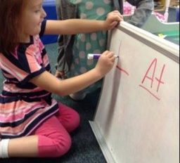 Two little girls writing on a white board.