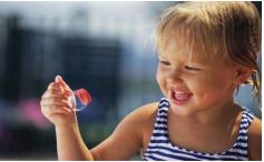 A little girl is holding a bubble wand.