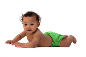 A baby in a green diaper laying down on a white background.