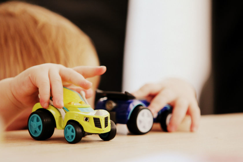 A child's hands playing with two play trucks.