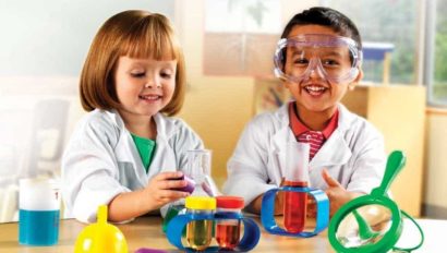 Two children in lab coats playing with toys.