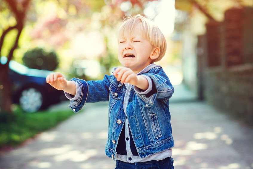 A young boy in a denim jacket is yelling.