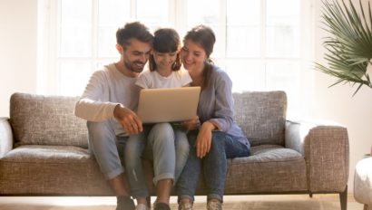 Two adults assisting a child on a computer.