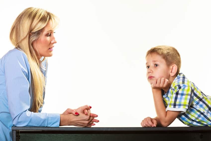 A woman talking to a boy at a desk.