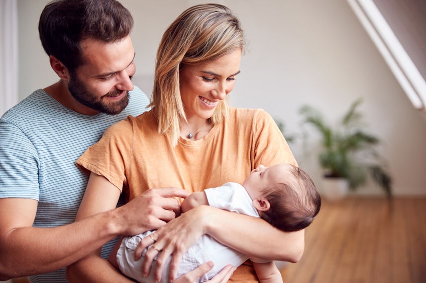 two young parents holding a baby.