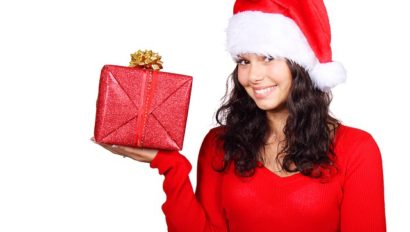A woman in a santa hat holding a gift box.