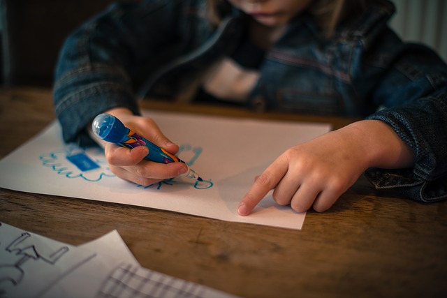 A child is drawing on paper with a pen.