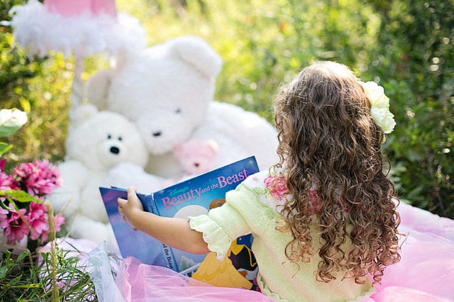 A little girl reading to her stuffed animals.