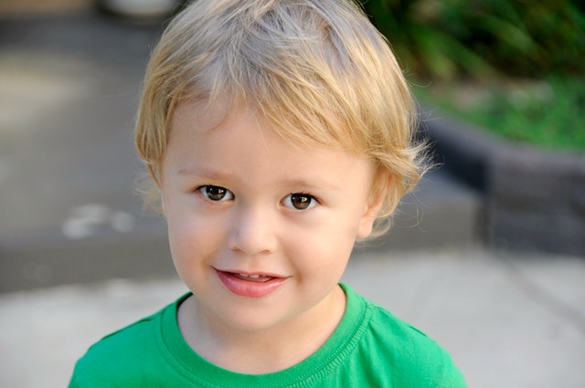 A young boy wearing a green t - shirt.