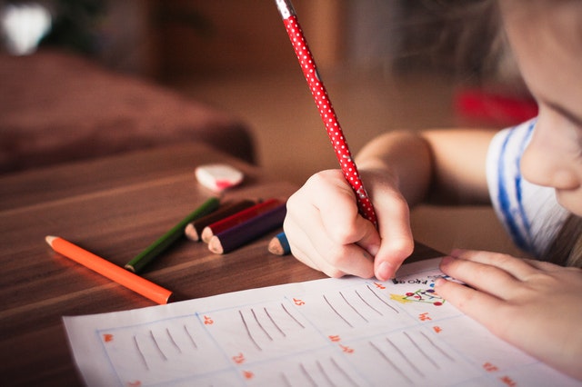 A little girl is writing on a piece of paper.