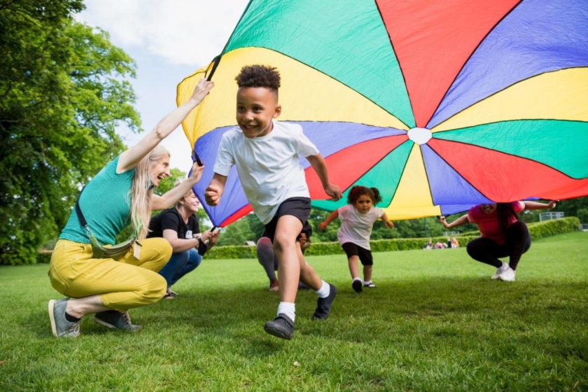 A group of children playing with a colorful parachute in a park.